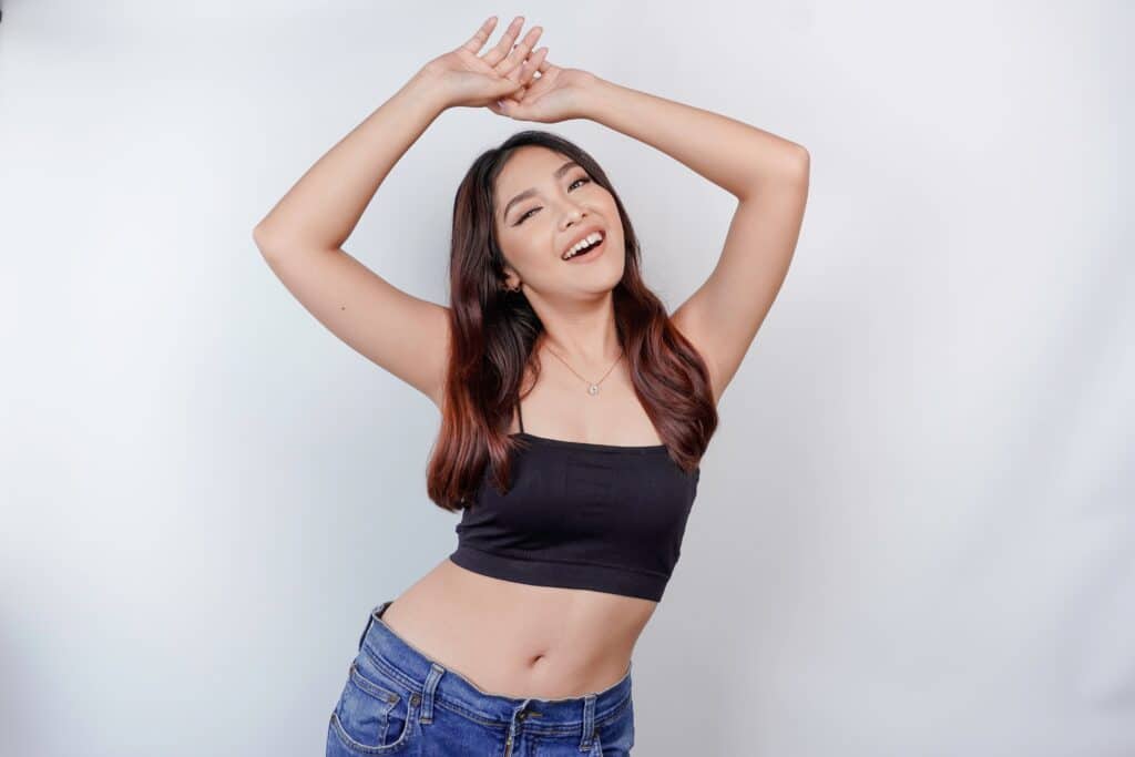 An Asian woman smiling with her arms in the air