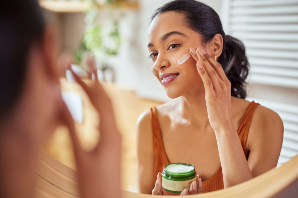 An image of a woman applying skin cream to her face