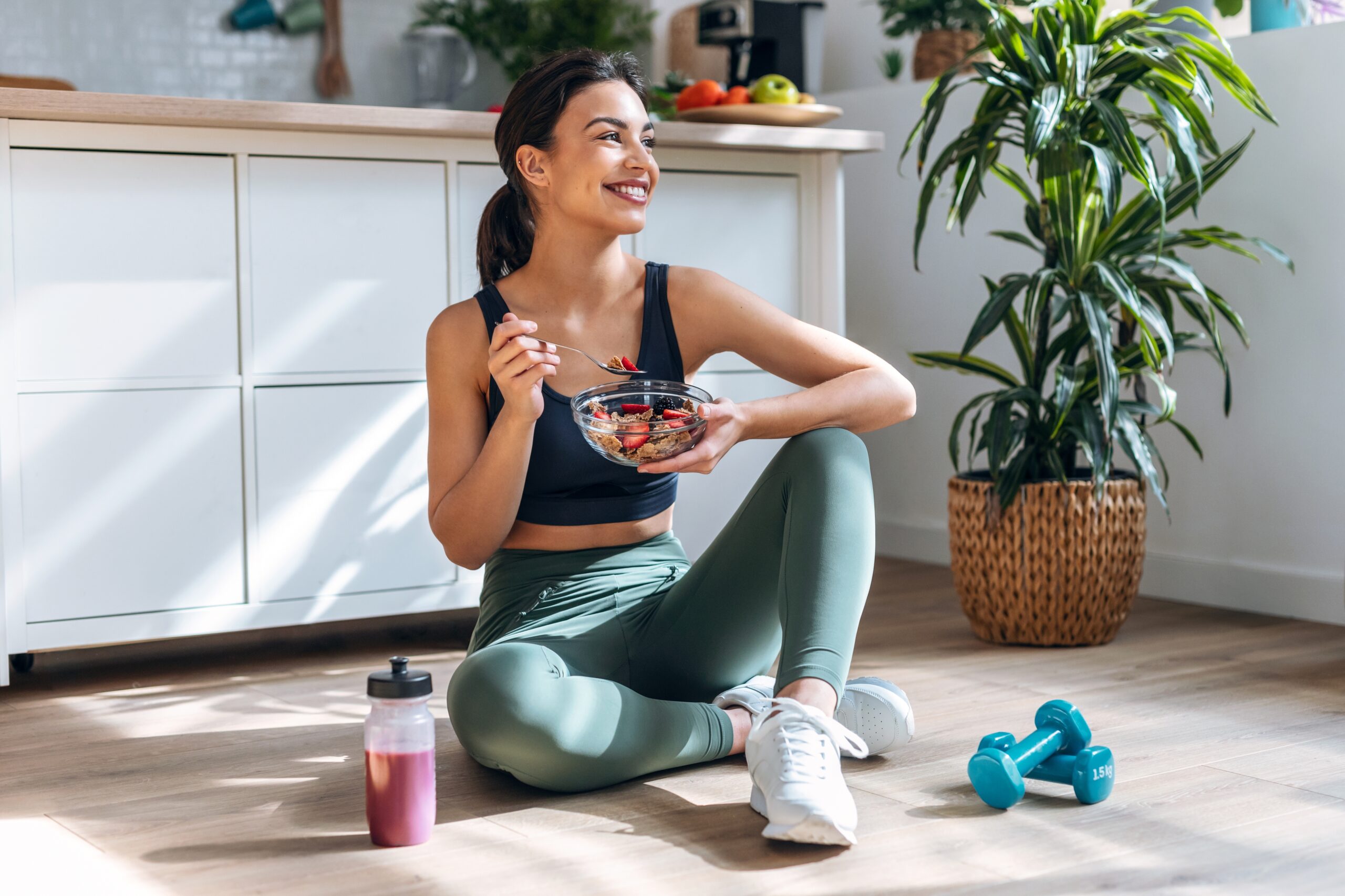 An image of a healthy brunette woman eating a bowl of granola