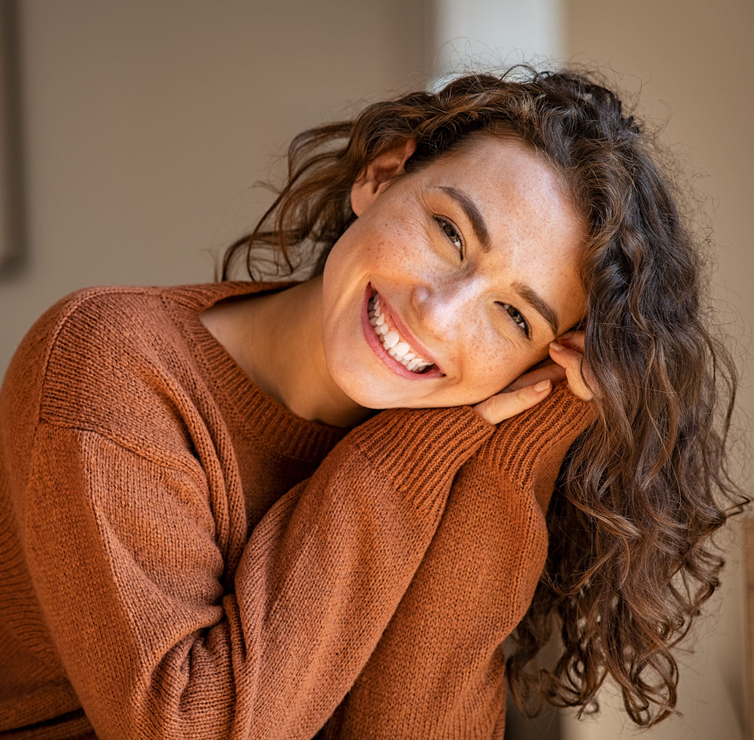 A brunette woman with curly hair smiling